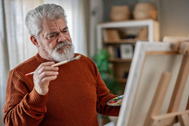 istock Senior artist painting on canvas at his home studio 2203495805