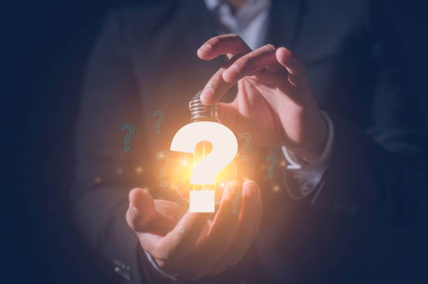 istock Businessman holding virtual light bulb in concept of idea Question mark concept. Problem and solution. Quiz, test, survey, support, knowledge, decision. FAQ 2203495904