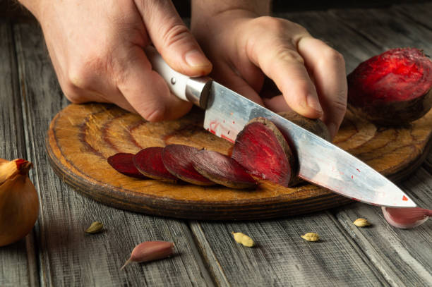istock Hands expertly slice vibrant beets on a wooden cutting board. Surrounding ingredients include garlic and shallots, adding to the rustic kitchen atmosphere 2203496372