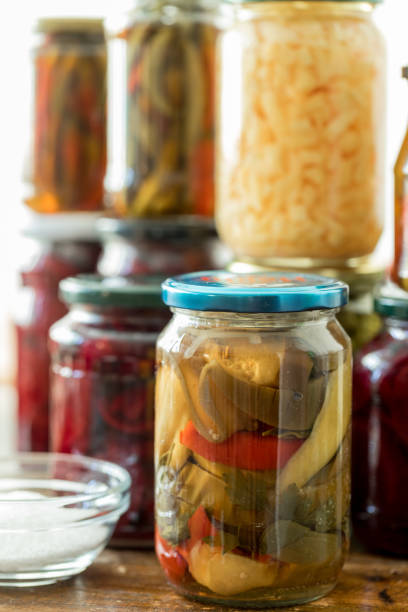 Fermented mixed vegetables in glass jar with jars filled with fermented vegetables on table