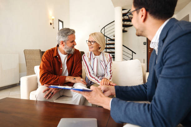 istock Smiling mature couple talking with financial advisor at home 2203503272