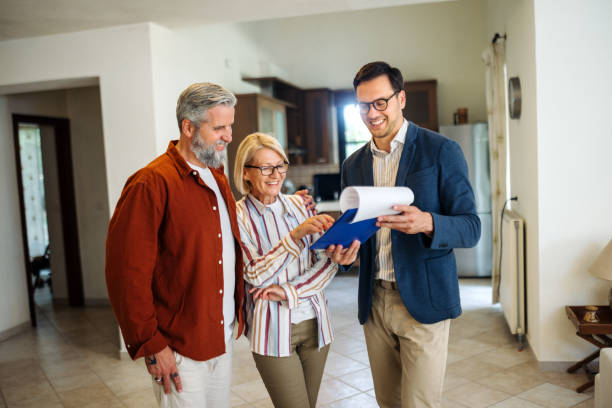 istock Male real estate agent showing document to mature couple while talking with them 2203503478