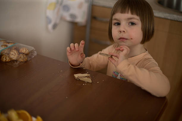 istock A happy child at a table, enjoying snacks in a cozy kitchen 2203505737