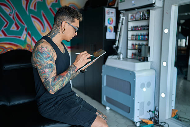 istock Tattoo artist drawing new tattoo design using a digital tablet in his modern studio, preparing for next client 2203507732