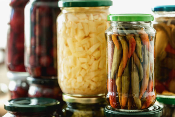 Fermented chilies in glass jar with jars filled with fermented vegetables