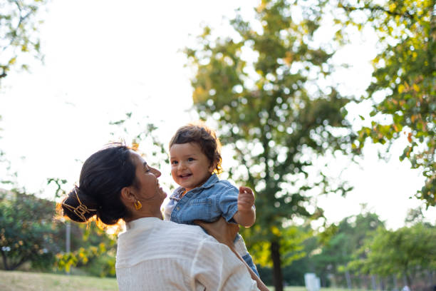 istock Mother lifting smiling toddler in a sunny park setting 2203510680