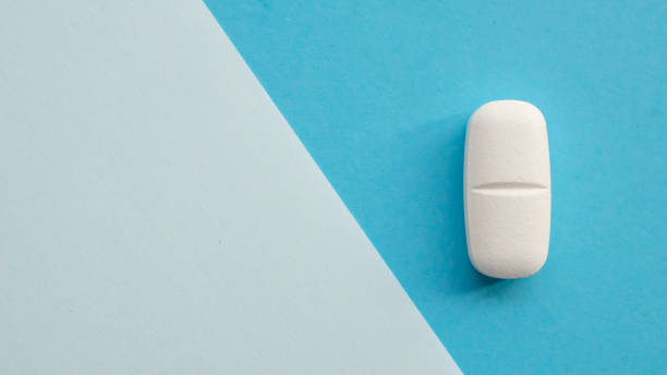 istock White medicine pill tablet on blue and white background 2203510717