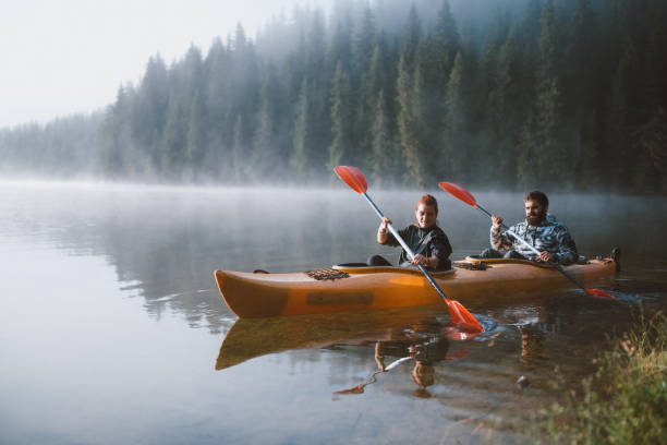 istock Adventurous couple kayaking through a serene mountain lake at dawn. 2203510934