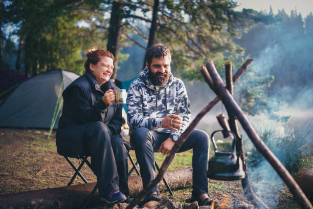 istock Couple having a steaming tea on a beautiful morning on camping vacation. 2203510946