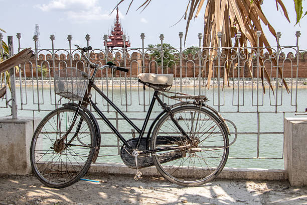 An old bicycle is lean on a railing over a water moat before the Royal Palace in Mandalay, Myanmar.