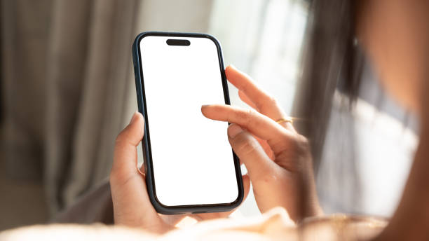 istock Close up of Woman hand holding using touch mobile phone white screen mockup. Back view 2203523802