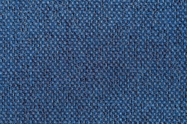 A macro close-up of blue denim fabric, highlighting the intricate weave and detailed texture. The tightly woven cotton threads showcase the classic structure of denim, commonly used in jeans and apparel.