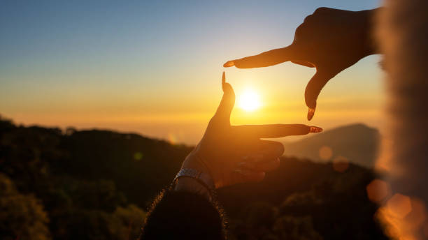 istock Closeup of woman hands making frame gesture capturing sunset, Future planning concept. 2203525055