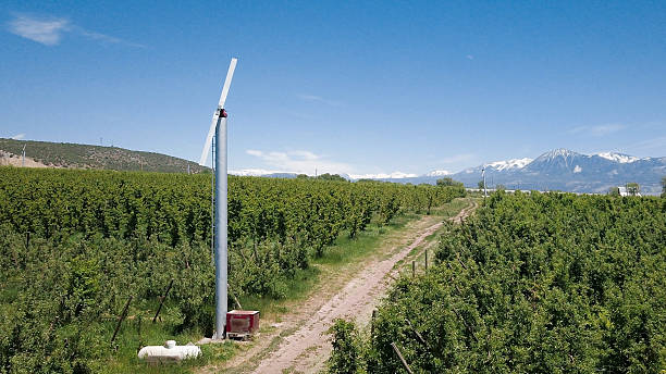 Arial photo of a beautiful apple orchard in Hotchkiss, Colorado featuring lush rows of trees, farm equipment, and the iconic mountain landscapes of Colorado.