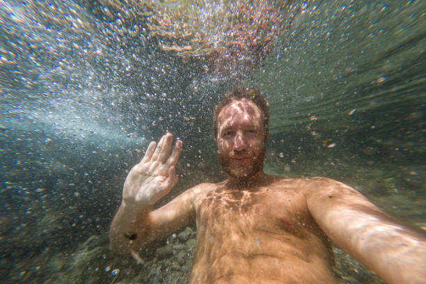 istock Man Smiling and Waving Underwater in a Clear Stream 2203526675