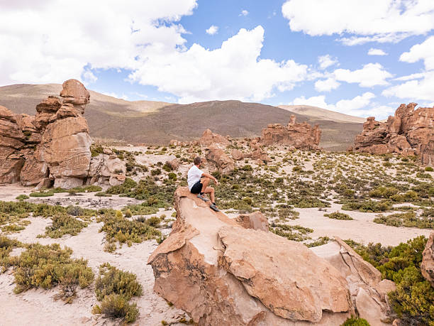 istock Man Sitting on Rock in Stunning Desert Landscape 2203527298