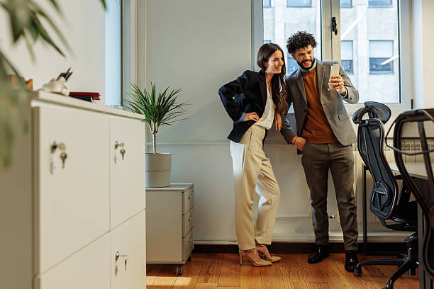 istock Colleagues using a smartphone and smiling in the office 2203529604