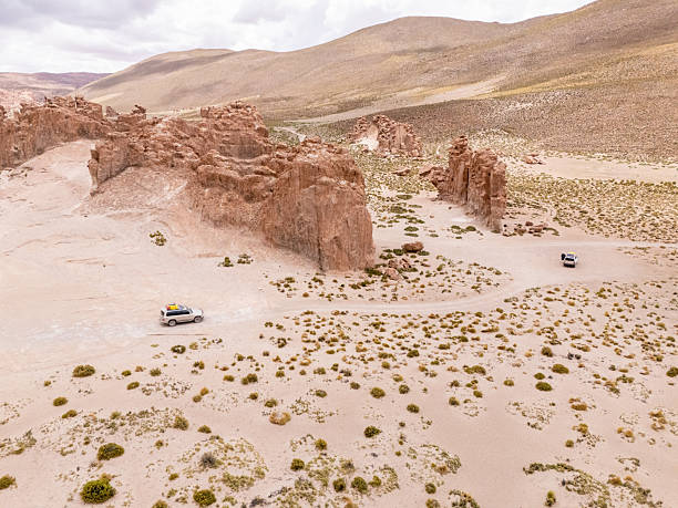 SUV driving through vast desert landscape with rugged rocks. Exploring isolated wilderness area.