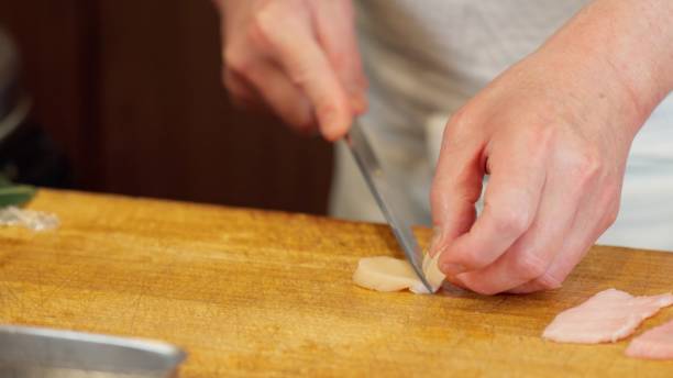istock The hands of a sushi chef cutting scallops 2203531076
