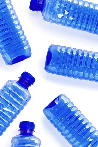 istock Clear single-use plastic water bottles isolated on white background close-up geometric pattern, minimal style, top view of bottled water, Pollution, environmental protection, plastic waste 2203533936