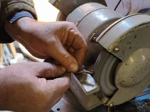 istock The hands of an elderly man with cracked skin hold a drill bit, which he sharpens on a machine in his home workshop 2203535811