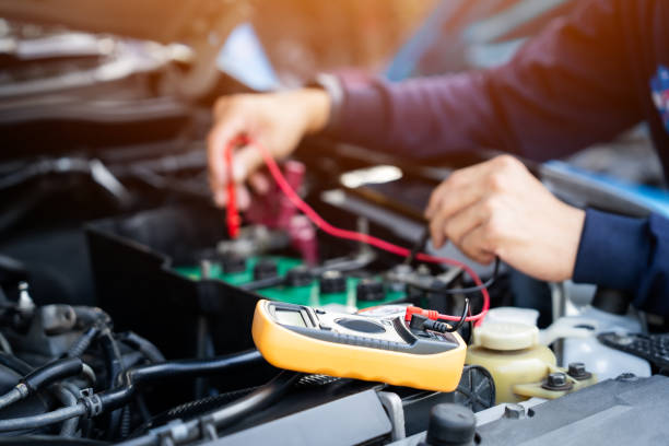 istock A mechanic is working on a car engine. He uses a multimeter to check the battery. 2203541074