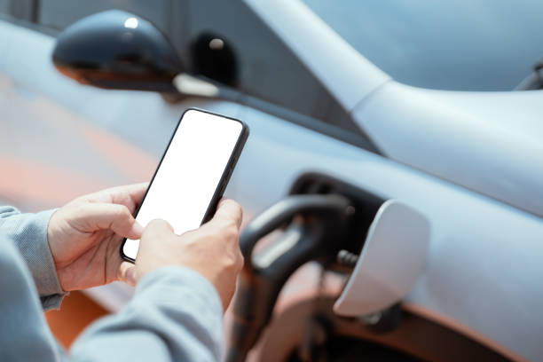 istock Driver using smartphone at electric vehicle charging station during early morning 2203546287
