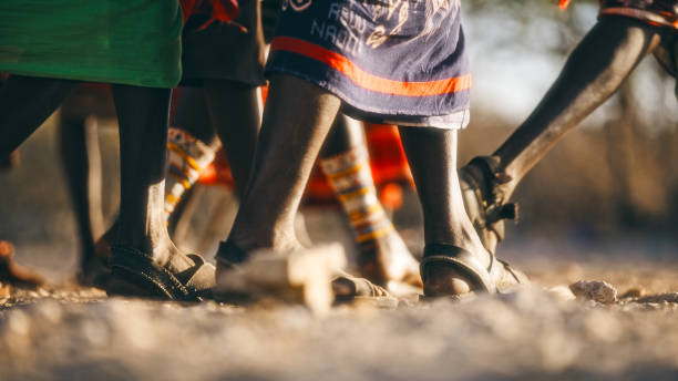 Samburu tribe members in traditional attire walk across dusty terrain, their leather sandals marking paths through rural Kenya. Cultural footwear reflects nomadic profession and ethnic heritage.