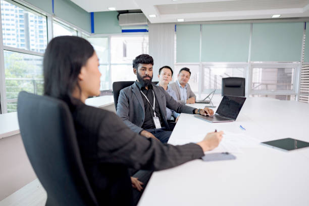 istock Business team having a meeting in a modern office with large windows and discussing work on laptops and tablets. 2203551653