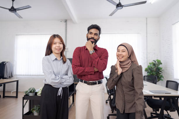 istock Diverse team of four young professionals standing confidently in modern open office with arms crossed, showcasing teamwork 2203552345