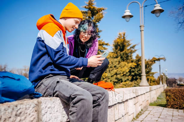 istock Two young adults on a date outdoors sitting in public park on sunny day 2203553677
