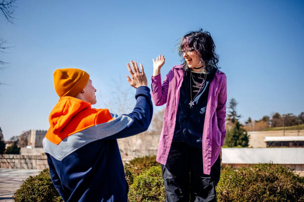 istock Two young adults on a date outdoors in public park on sunny day taking high-five 2203553930