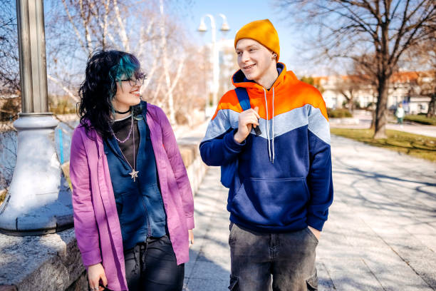 istock Two young adults on a date walking outdoors in public park on sunny day 2203554029