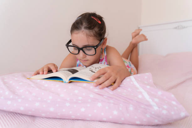 istock Girl laying on bed reading book 2203554212