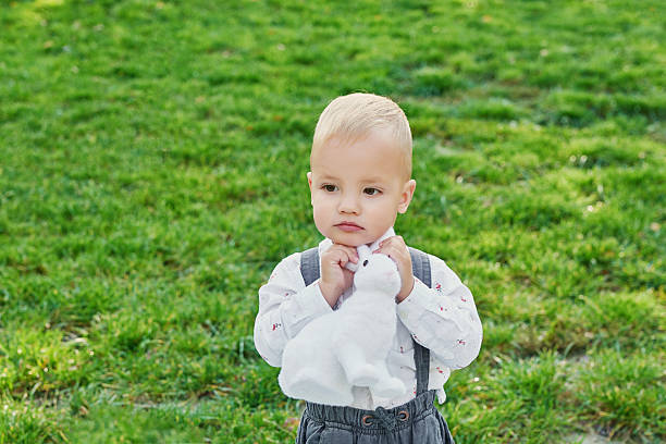 Happy Easter bunny. Child having fun outdoor. Kid playing with eggs and rabbit on green grass. Spring holidays concept. Easter Greeting Card Template. Easter baby boy with bunny and eggs.