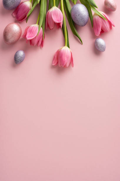 istock Flat lay vertical composition featuring pink spring tulips and pastel colored eggs on pink background, perfect for Easter and spring themes 2203556781