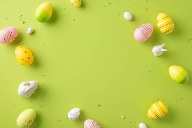 istock Festive Easter scene with decorative eggs and rabbit figurines arranged on a green surface 2203556782