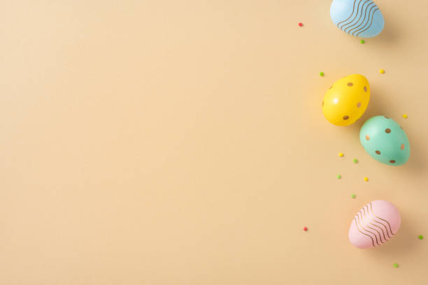 istock Four multicolored Easter eggs arranged diagonally on a pastel beige background with small scattered confetti dots, offering a minimal and festive composition 2203556804