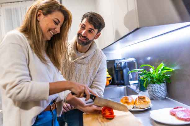 istock Couple preparing dinner together, slicing tomatoes in modern kitchen 2203557037