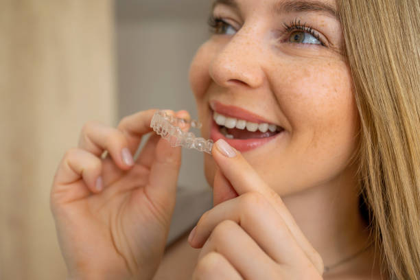 istock Smiling woman holding a clear orthodontic aligner for her teeth 2203557517