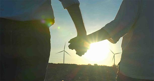 istock Holding Hands at Sunset in a Wind Farm. 2203557990