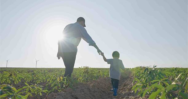 istock Father and Son Walking Hand in Hand Through Farmland. 2203558398