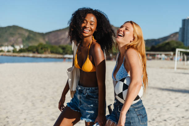 istock Two joyful friends laughing together on a sunny beach day 2203559392