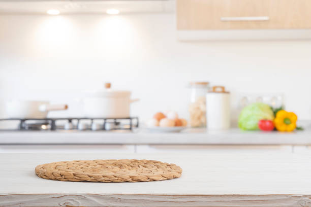 istock Woven round stand for hot dish on bleached wooden table over blurred kitchen room cooking counter background 2203562616