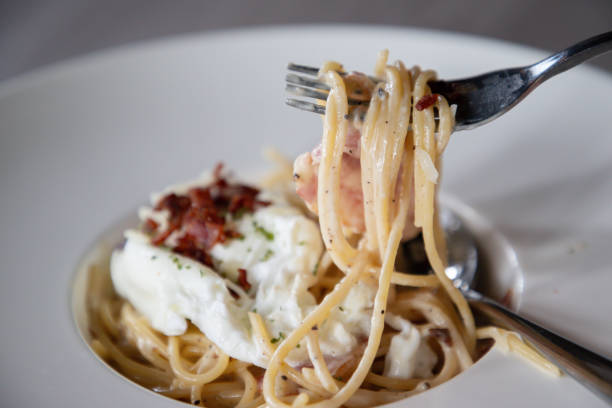istock A fork is holding a piece of pasta with bacon on top 2203563037