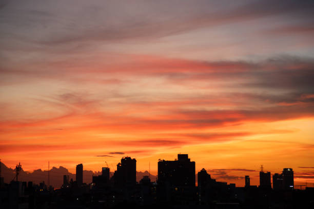 The sky is orange and the sun is setting. The city below is lit up with lights