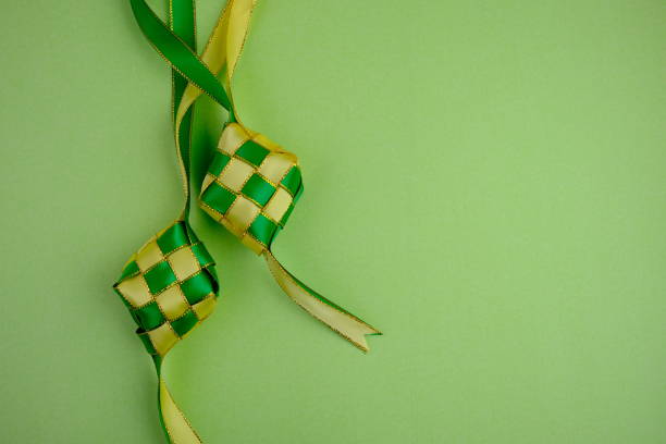istock hand crafted ketupat or rice dumpling packaging from ribbon isolated on green background. Ramadan and Hari Raya Eid al-Fitr decoration for template, card, and background 2203563056