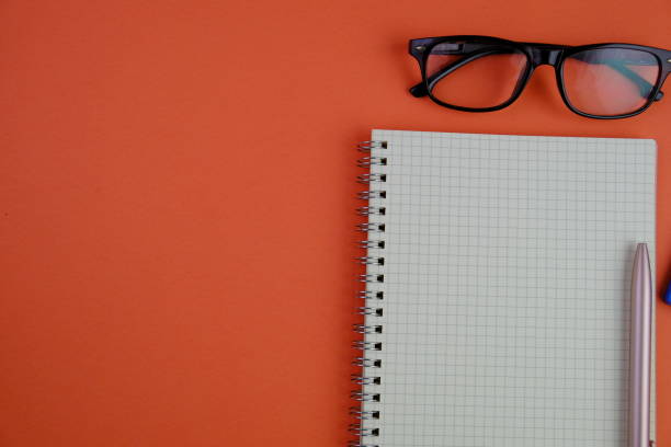 istock flat lay of a blank note book for text space. Educational and financial concept with text space on white background. surrounded by tools such as pen, alarm clock and calculator 2203564743