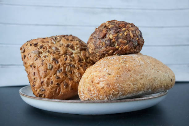 istock A selection of fresh whole grain and seeded bread rolls stacked on a ceramic plate against a light wooden background. 2203565581
