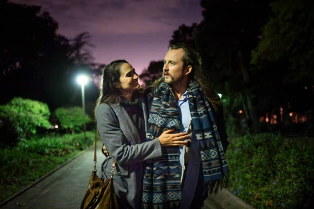 Romantic couple enjoying a peaceful walk in a public park at night, seen strolling together